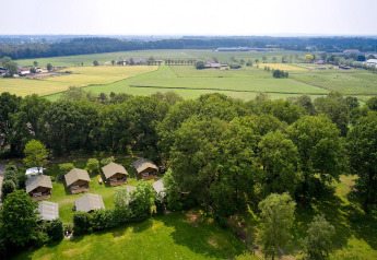 Vista aérea de las tiendas safari Villatent Nomad en Recreatiepark de Lucht, rodeadas de campo verde.