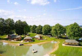 Aerial view of Villatent Nomad safari tents by a pond at Camping Betuwe, Netherlands, on a sunny day.