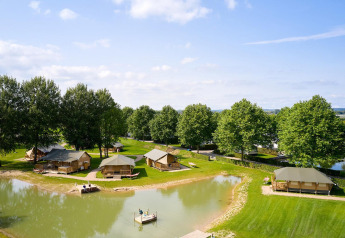 Aerial view of Villatent Nomad safari tents by a pond at Camping Betuwe, Netherlands, on a sunny day.