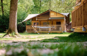 Tienda safari Villatent Ranger en Recreatiepark de Lucht, Países Bajos, rodeada de árboles y naturaleza.