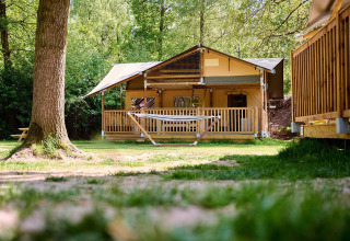Tienda safari Villatent Ranger en Recreatiepark de Lucht, Países Bajos, rodeada de árboles y naturaleza.