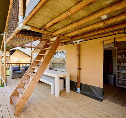 Houten buitenterras met trap en zithoek aan de Villatent Ranger safaritent, ideaal voor gezelligheid.