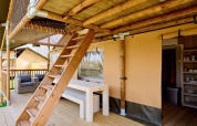 Terraza de madera al aire libre con escaleras y área de comedor en la tienda safari Villatent Ranger.