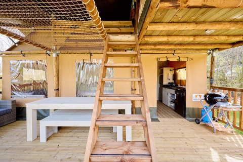 Interior de tienda safari Villatent Ranger con escaleras de madera, mesa de comedor y área de cocina abierta.