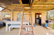 Interieur van een safaritent Villatent Ranger met houten trap, eettafel en een open keukenruimte.