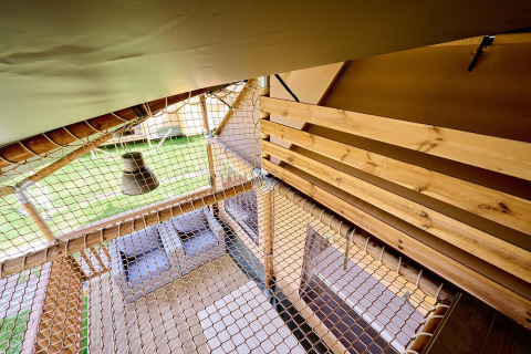 Vue intérieure de la tente safari Villatent Ranger avec plancher en bois, filet et vue extérieure.