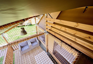 Vista interior de la tienda safari Villatent Ranger con suelo de madera, pasarela de red y vistas al exterior.