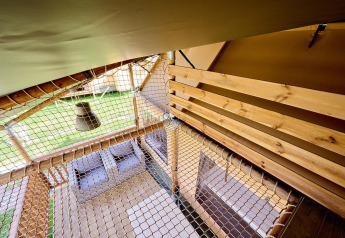 Interieur aanzicht van Villatent Ranger safaritent met houten vloer, net en uitzicht naar buiten.