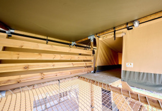 Binnenkant van de Villatent Ranger safaritent met houten plafond, netvloer en toegang tot een extra ruimte.