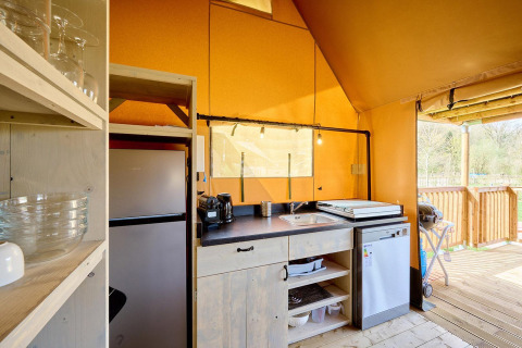 Gezellige keuken in een Villatent Ranger safaritent met moderne apparaten en zicht op een houten terras.