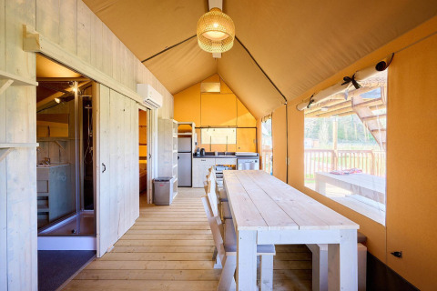 Interieur van de Villatent Ranger safaritent met keuken, eettafel en een groot raam met uitzicht.