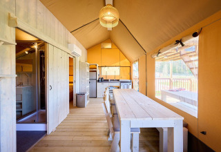 Interieur van de Villatent Ranger safaritent met keuken, eettafel en een groot raam met uitzicht.