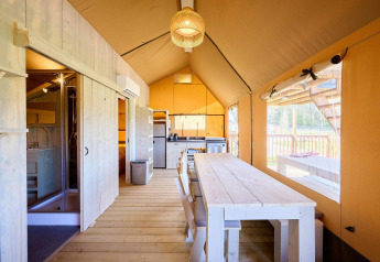 Vista interna della tenda safari Villatent Ranger con cucina, tavolo da pranzo e ampia finestra panoramica.