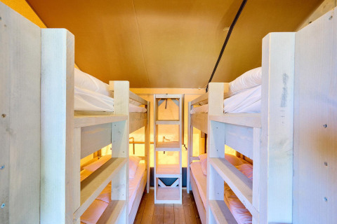Intérieur d’une tente safari Villatent Ranger avec quatre lits superposés en bois et lumière chaleureuse.
