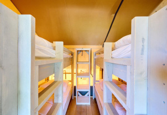 View inside a Villatent Ranger safari tent featuring four wooden bunk beds and warm ambient lighting.