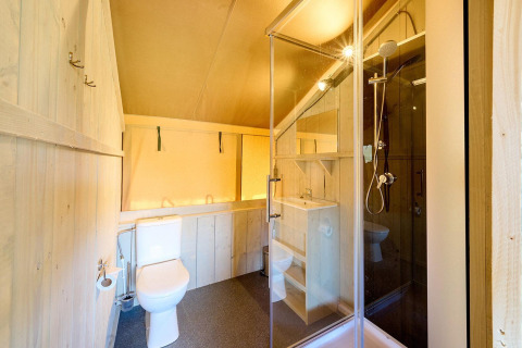 Vista interior de un baño en una tienda safari Villatent Ranger con ducha, inodoro y lavabo.