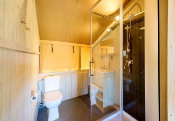 Vista interna di un bagno in una tenda safari Villatent Ranger con doccia, WC e lavandino.
