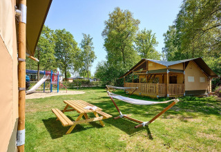 Tienda safari Villatent Ranger con área de juegos, mesa de picnic y hamaca en Recreatiepark de Lucht.