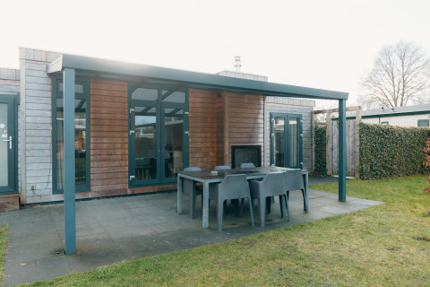 Terraza exterior con mesa de comedor y sillas en Veluwe Villa + sauna, Holiday park De Boshoek, Países Bajos.
