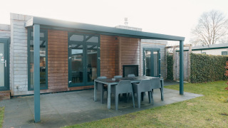 Outdoor patio with dining table and chairs at Veluwe Villa + sauna, Holiday park De Boshoek, Netherlands.