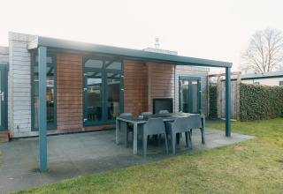 Outdoor patio with dining table and chairs at Veluwe Villa + sauna, Holiday park De Boshoek, Netherlands.