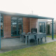 Outdoor patio with dining table and chairs at Veluwe Villa + sauna, Holiday park De Boshoek, Netherlands.