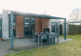 Outdoor patio with dining table and chairs at Veluwe Villa + sauna, Holiday park De Boshoek, Netherlands.