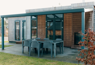 Terras met zes stoelen bij Veluwe Villa + sauna, moderne houten lodge met overdekte buitenruimte.