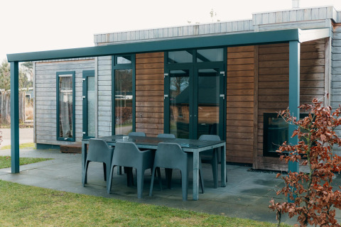 Outdoor dining area with six chairs at Veluwe Villa + sauna, modern wooden lodge with covered terrace.