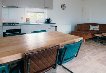 Cuisine et salon modernes à Veluwe Villa + sauna, table en bois, chaises colorées et canapé marron.