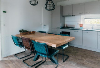 Eetruimte en keuken in Veluwe Villa + sauna, met houten tafel, blauwe stoelen en modern design.