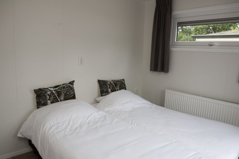 Camera da letto con due letti singoli, coperte bianche e cuscini con lupi a Veluwe Villa + sauna, De Boshoek.