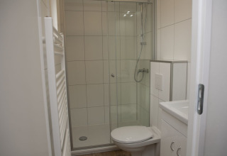 Baño moderno con ducha, inodoro e interior blanco en Veluwe Villa + sauna, Holiday park De Boshoek, Países Bajos.