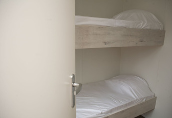 Et kig ind i et værelse med køjesenge og hvide lagner i Veluwe Villa + sauna i De Boshoek, Holland.