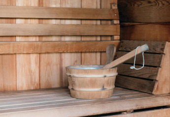 Intérieur d’un sauna en bois à Veluwe Villa + sauna avec banc, seau et louche pour se détendre.