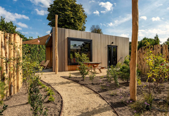 Moderne Tiny Wellness Cabin bij Holiday Park De IJsvogel in Nederland, omringd door tuin en natuur.