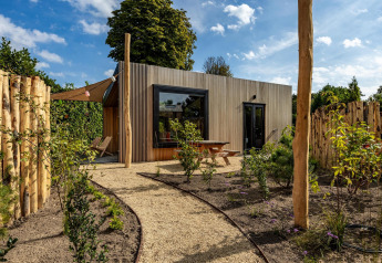 Moderne Tiny Wellness Cabin ved Holiday Park De IJsvogel i Holland omgivet af planter og natur.