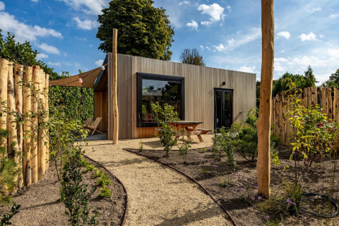 Moderne Tiny Wellness Cabin bij Holiday Park De IJsvogel in Nederland, omringd door tuin en natuur.