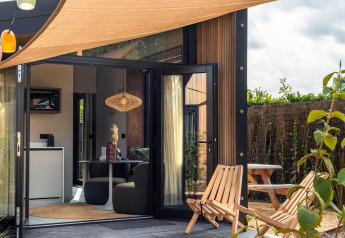 Accogliente patio e interni moderni di una Tiny Wellness Cabin al Holiday Park De IJsvogel, Paesi Bassi.