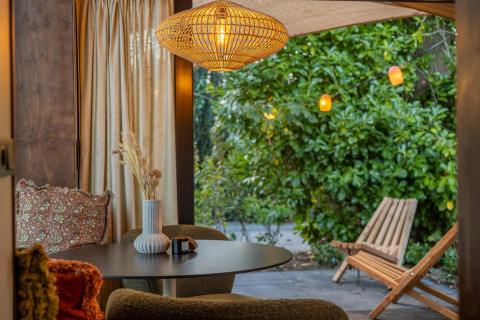 Accogliente interno della Tiny Wellness Cabin all’Holiday Park De IJsvogel con vista su un rigoglioso giardino.