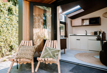 Vista dell'interno della Tiny Wellness Cabin al Holiday Park De IJsvogel con sedie e cucina moderna.