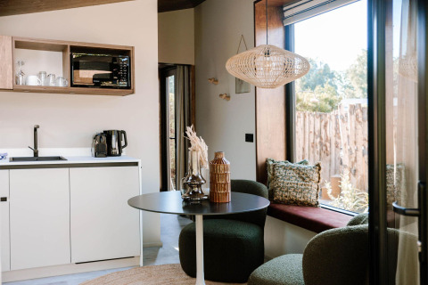 Interior moderno con cocina, mesa de comedor y gran ventana en Tiny Wellness Cabin, Holiday Park De IJsvogel, Países Bajos.