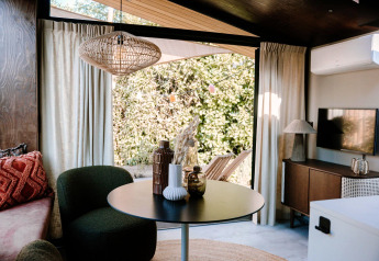 Lys og moderne indretning i Tiny Wellness Cabin på Holiday Park De IJsvogel, med udsigt til haven.