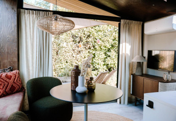 Intérieur lumineux et moderne de la Tiny Wellness Cabin au Holiday Park De IJsvogel, vue sur le jardin.