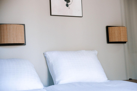 Camera da letto nella Tiny Wellness Cabin presso Holiday Park De IJsvogel, con cuscini bianchi e lampade a muro.