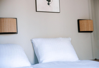 Camera da letto nella Tiny Wellness Cabin presso Holiday Park De IJsvogel, con cuscini bianchi e lampade a muro.