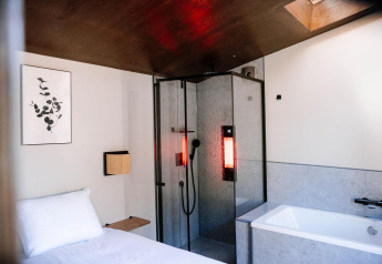 Moderne, kompakt wellnesshytte med seng, brusebad med rødt lys og badekar på Holiday Park De IJsvogel.