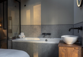 Moderne badeværelse med badekar, håndvask og håndklæder i Tiny Wellness Cabin, De IJsvogel, Holland.
