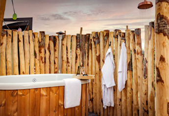 Udendørs wellnessområde med træbadekar, badekåber og bruser i Tiny Wellness Cabin på De IJsvogel.