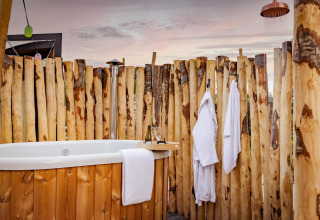 Area benessere all'aperto con vasca, accappatoi e doccia alla Tiny Wellness Cabin, De IJsvogel, Paesi Bassi.